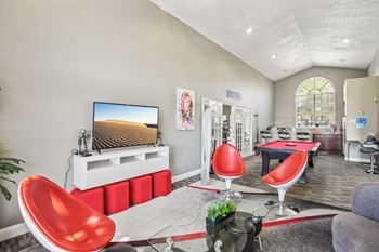 A modern living room with a red chair and a flat screen TV.